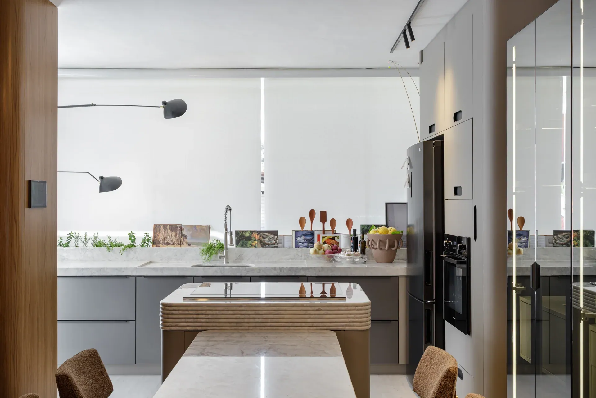 Cozinha do showroom Oca com ilha, armários cinza e torre de eletrodomésticos